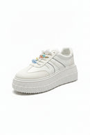 White sneaker with decorative elements on a dark surface