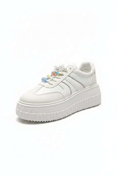 White sneaker with decorative elements on a dark surface