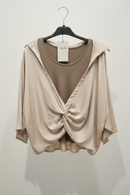 Beige top with a knot detail on a hanger against a white background