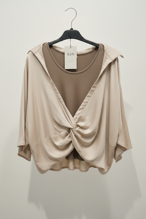 Beige top with a knot detail on a hanger against a white background