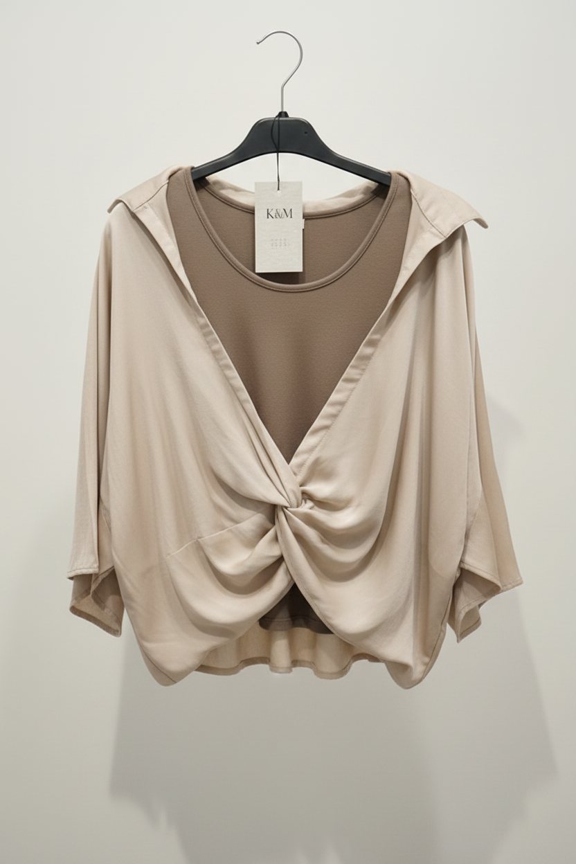 Beige top with a knot detail on a hanger against a white background