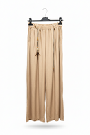 Beige wide-leg pants hanging on a black hanger against a white background