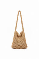 Hand holding a woven handbag in a clothing store.