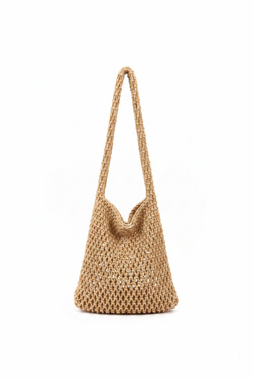 Hand holding a woven handbag in a clothing store.