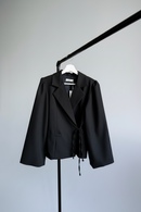 Black jacket on a hanger against a plain background