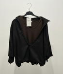 Black blouse with brown accents on a hanger against a white background