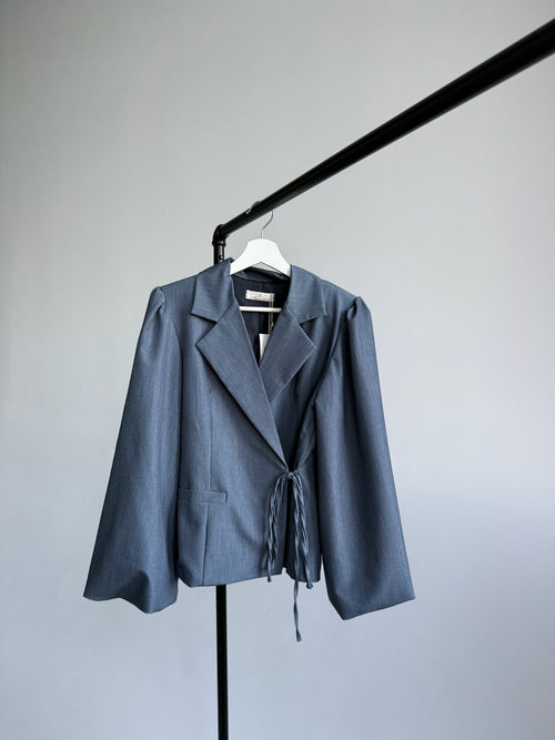 Blue jacket on a hanger against a plain background