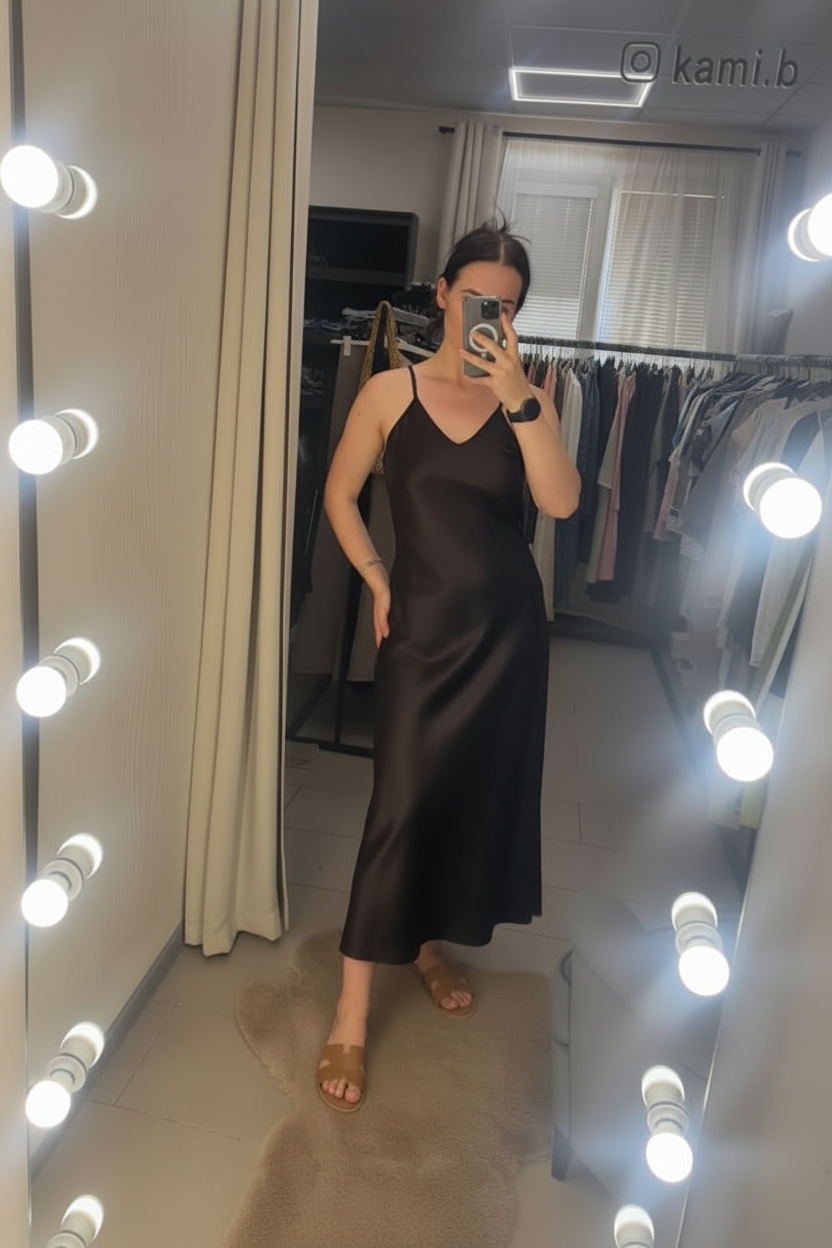 Person wearing a brown dress in a room with a mirror and lights.