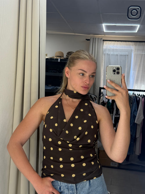 Person wearing a brown dress with white polka dots taking a mirror selfie.