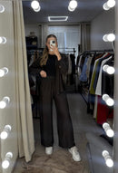 Person taking a mirror selfie in a clothing store with lights around the mirror.