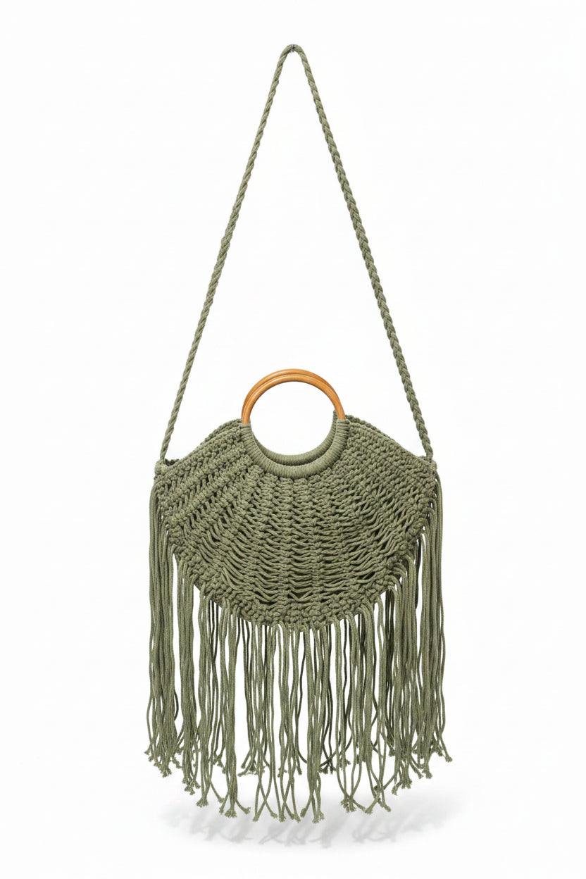 Green macrame handbag with fringe and wooden ring handle on a white background