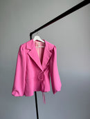 Pink blazer on a hanger against a gray background