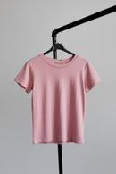 Pink t-shirt on a hanger against a gray background