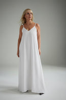 Woman wearing a white slip dress against a plain background
