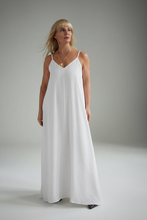 Woman wearing a white slip dress against a plain background