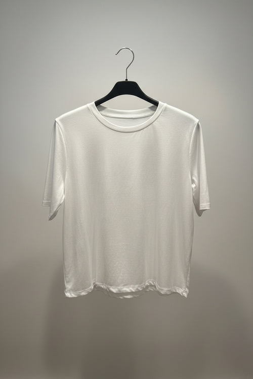 White t-shirt on a black hanger against a gray background